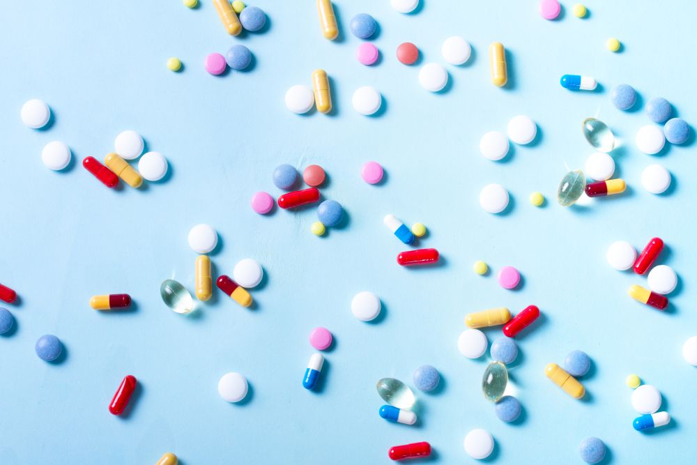 Assorted medical pills on blue background, top view