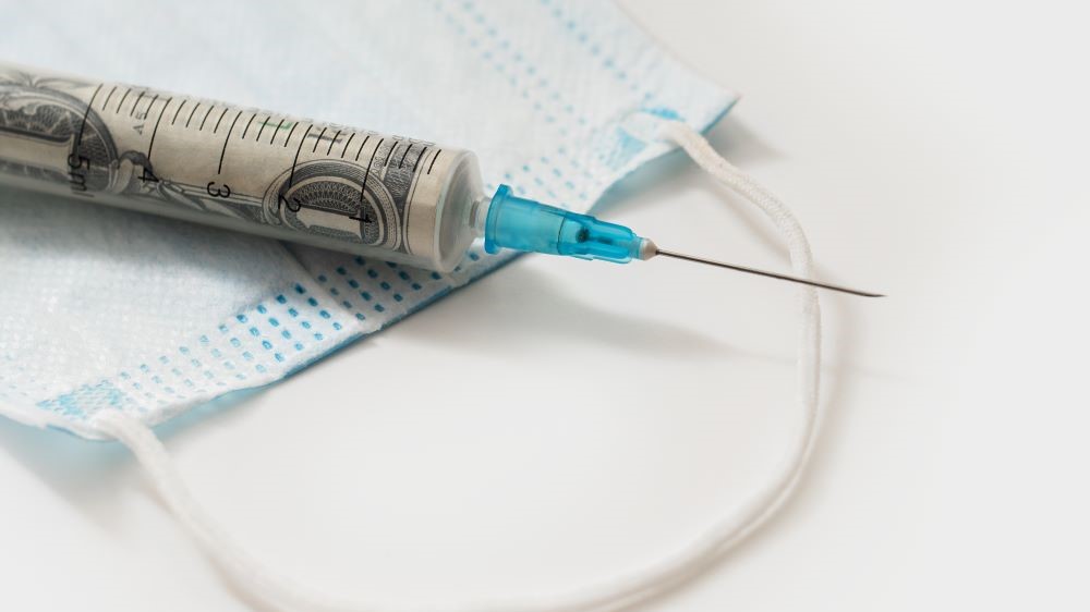 Hypodermic needle and a medical face mask. The needle is filled with a dollar bill.