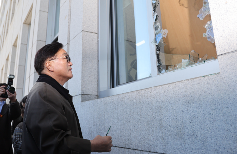The Speaker of the National Assembly of South Korea is looking at the broken windows of the National Assembly building caused by the invasion of the martial law troops.