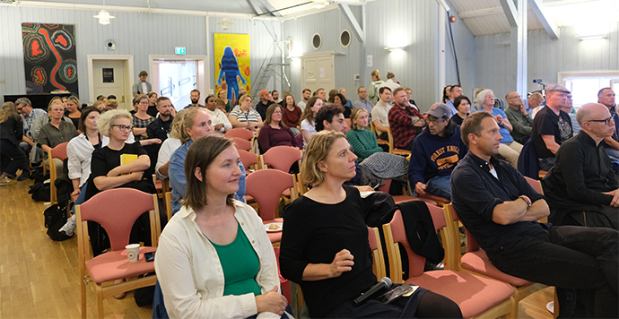 50-100 mennesker sittende på stolrader