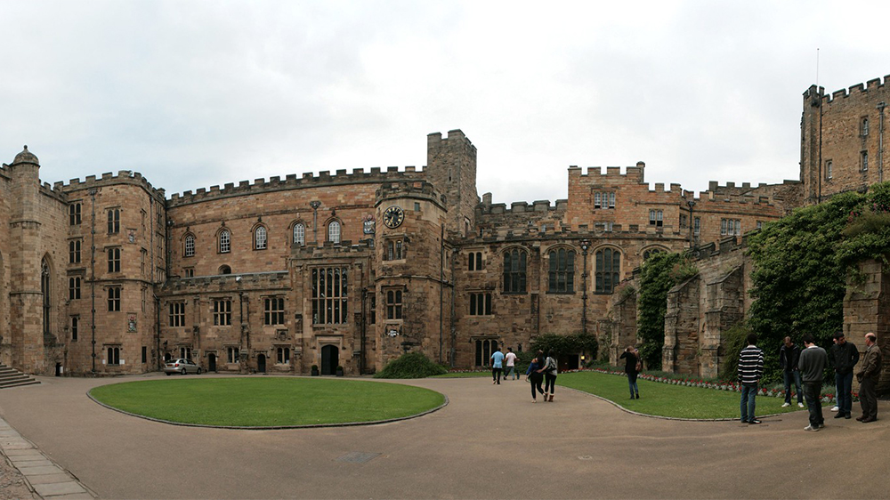 Large, old brick building with some people in front